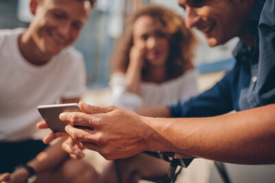 Three people looking together at a phone. Three people looking together at a phone.